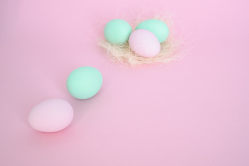 Eggs in nest of pink and mint color, several next to pink background. Easter concept