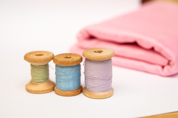 Sewing accesories and spools of thread on the pink background