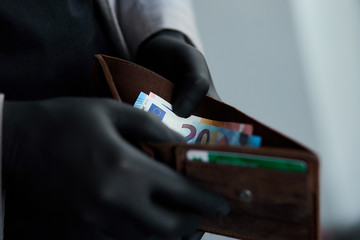 Man holding a wallet with money euro in hand in black medical gloves.