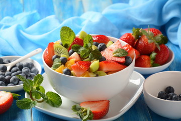Bowl of healthy fresh colorful fruit salad on wooden background. Top view.Fruit salad with strawberry, blueberry, sweet cherry, kiwi.Vegetarian food concept. Rustic wooden background