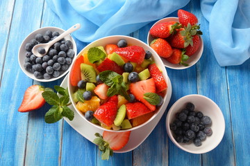 Bowl of healthy fresh colorful fruit salad on wooden background. Top view.Fruit salad with strawberry, blueberry, sweet cherry, kiwi.Vegetarian food concept. Rustic wooden background
