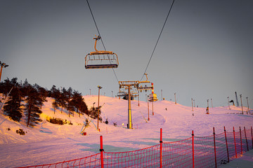 Silhouettes of skiers on chair lifts in the evening