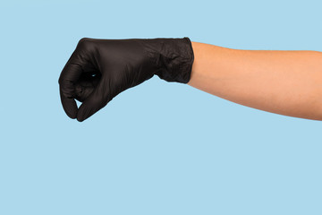 hand in a black medical glove holds an object on a blue background. Mock up, you can insert your product for advertising