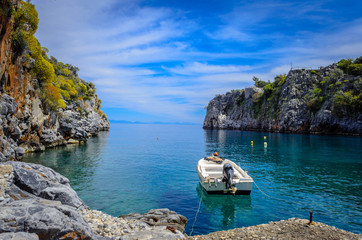 Peloonnese Greece -Beautiful seascape in Mani with crystal waters, big cliffs and small boat.