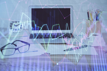 Stock market graph on background with desk and personal computer. Double exposure. Concept of financial analysis.