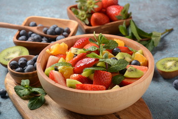 Bowl of healthy fresh colorful fruit salad on wooden background. Top view.Fruit salad with strawberry, blueberry, sweet cherry, kiwi.Vegetarian food concept. Rustic wooden background