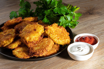 Fried potato pancakes with sauces and fresh herbs closeup. Belorussian or Ukrainian national cuisine