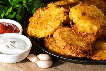 Fried potato pancakes with sauces and fresh herbs closeup. Belorussian or Ukrainian national cuisine