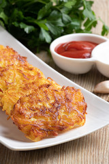 Potato pancakes on a white plate with sauces and fresh herbs