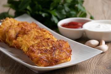 Potato pancakes on a white plate with sauces and fresh herbs