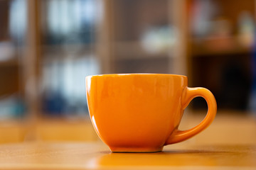 Coffee cup on the table against the background of shelving.