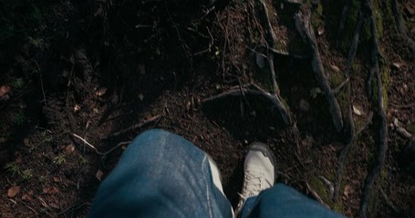 POV on male legs wear jeans and adventure boots or shoes walk on forest trail or during hike or trip in mountains. Man walk in forest. Concept outdoor lifestyle - Powered by Adobe