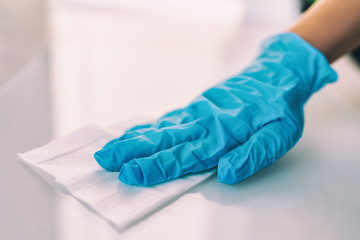 Surface disinfecting home cleaning with sanitizing antibacterial wipes protection against COVID-19 spreading wearing medical blue gloves. Sanitize surfaces prevention in hospitals and public spaces. - obrazy, fototapety, plakaty