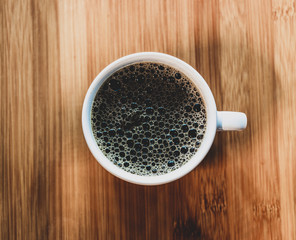  Cup of coffee seen from above on wooden table.