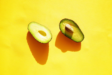 Avocado with contrasting shadows on a yellow background. Shadow trend. Green vegetables
