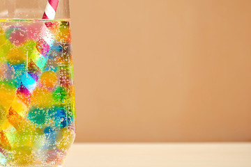 Front view of the cocktail glass with many colorful jelly balls and fizzy drink inside with red-white straw. Copy space for your text. Background for advertisement.