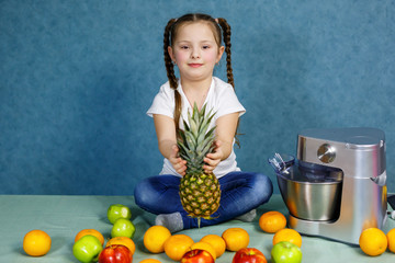 little girl in a white t-shirt loves fruits. She holds a pineapple in her hands