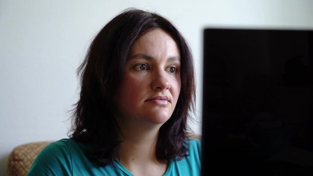 woman sitting befor computer sneezing into cubit