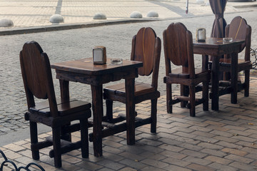 Wooden tables and chairs in a retro style street cafe without people