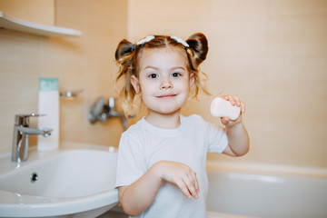 A child shows soap in bathroom. A kid is washing hands with anti-infective soap. Baby girl washing...