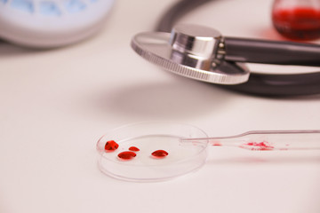 medical laboratory bowl with blood drops, stethoscope, flasks, concept of virology, epidemic, blood...