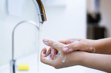 Woman washing hands under the water tap. Hygiene concept hand detail.