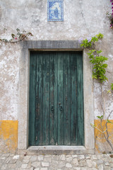 Óbidos, Portugal: Alte grüne Haustür mit Keramik Fliesen oberhalb und einer Darstellung Relief...