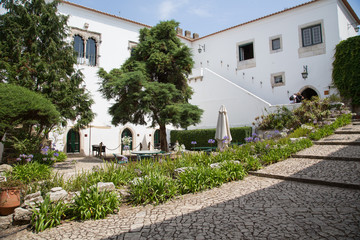 Fototapeta na wymiar Dorf Óbidos, Portugal: Garten Innenhof mit Naturstein Treppen umrahmt von Reihen mit lila und weissen Schmucklilien