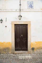 Fototapeta na wymiar Óbidos, Portugal: Alte Haustür mit Keramik Fliesen oberhalb und einer Darstellung Relief aus der Bibel (heilige Maria)