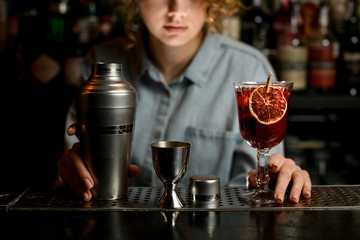 Shacker and other tools for making cocktail stand on bar counter.