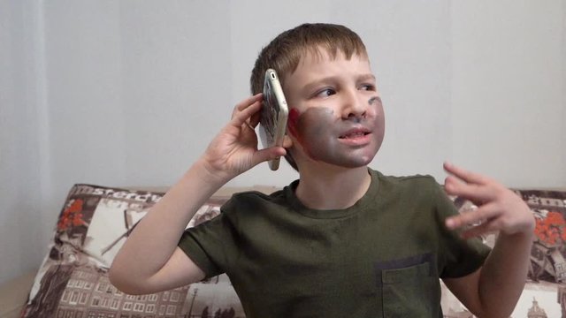 boy with face paint talking on the phone, gesturing