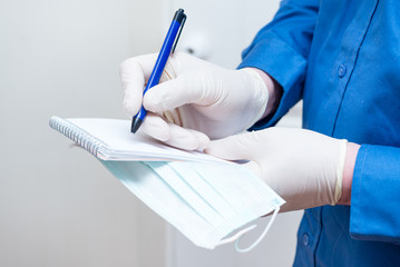 Man writes a note in a notebook during a coronavirus epidemic, wearing latex gloves