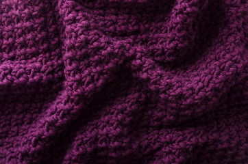 Fototapeta na wymiar Folds of knitted fabric as a background.Top view of dark purple knitting texture