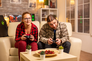 Gamers couple playing video games on the TV with wireless controllers in hands