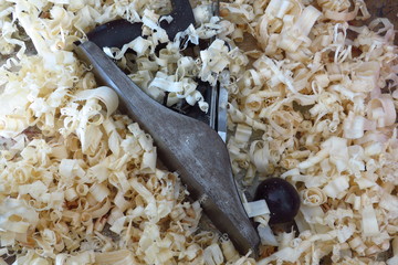 An old fashioned wood plane lies amongst the wood shavings it created.