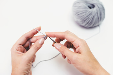 Start knitting. Crochet Hook and gray yarn in hands on the white background.Women's hobby. 