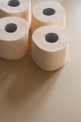 rolls of toilet paper peach beige color on beige background