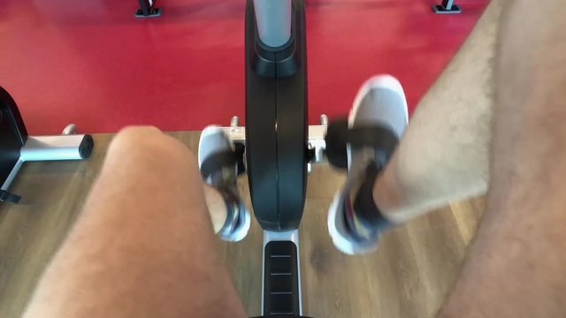 POV man in the gym pedals an exercise bike