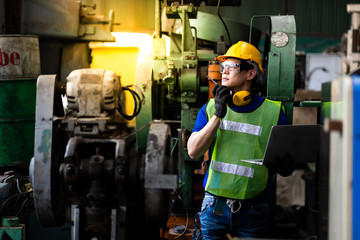 Portrait Engineer man working with computer laptop or tablet at factory Equipment. Chief Engineer in the Hard Hat Holds Laptop at the industrial facility.