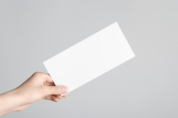 DL Flyer Mock-Up - Male hands holding a blank flyer on a gray background.