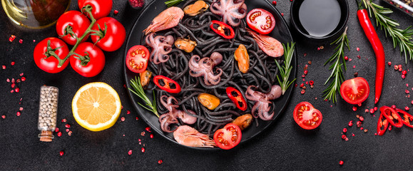Black seafood pasta with shrimp, octopus and mussels on black background. Mediterranean gourmet food © chernikovatv