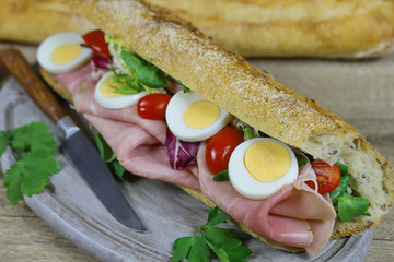 sandwich au jambon et crudités sur une planche à découper