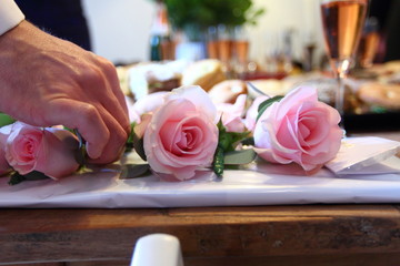 hand picking up a pink rose from a table