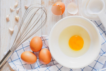Eggs in a cup and whisk, beat eggs on a wooden table