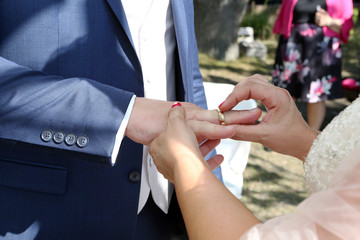 Die Braut steckt den Bräutigam, den Ehering an den Finger, an ihre Hochzeit 