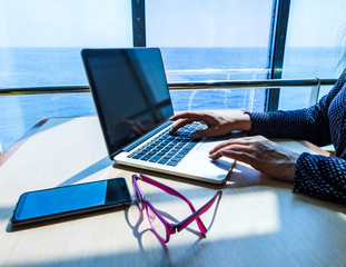 Woman using laptop computer, searching the web, browsing information while traveling on a ship
