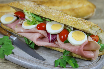 sandwich au jambon et crudités sur une planche à découper