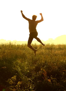 Silhouette Of A Man Jumping For Joy In The Sunset