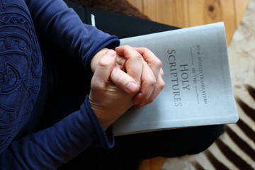 Obraz premium woman's hands folded in prayer while resting on a bible