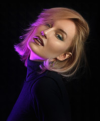 Sexy young woman posing on a dark background with neon light. Blonde girl with pink hair portrait...
